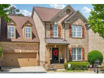 Charming brick two-story home with a well-manicured lawn, dormer windows, and a lovely red wreath on the front door at 2254 Donnington Nw Ln, Concord, NC 28027