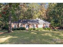 Charming red brick home with a well-manicured lawn and mature trees at 2643 Rolling Hills Dr, Monroe, NC 28110