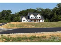Beautiful two-story white farmhouse with a dark roof and lush greenery in the background at 4034 Daugherty Rd, China Grove, NC 28023