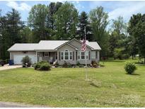 Charming single-story home featuring a metal roof, lush lawn, and a welcoming front porch at 1025 Bee Line Ln, Salisbury, NC 28147
