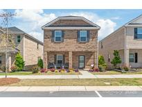 Charming two-story brick home featuring a covered front porch and manicured landscaping at 1316 Colgher St, Mint Hill, NC 28227