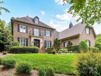 Elegant brick home with a manicured lawn, dark shutters, and a balcony at 14650 Trading Path Way, Charlotte, NC 28277