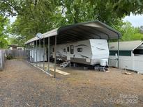 White RV with a metal carport cover with surrounding gravel and additional storage shed at 148 Sunshine Trl # A165, Mount Gilead, NC 27306