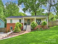 Charming home with brick and painted facade, inviting front porch, and lush lawn and landscaping at 1733 Piccadilly Dr, Charlotte, NC 28211