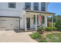 Charming home featuring a welcoming front porch, black door with a wreath, and beautiful landscaping at 2206 Mills Harris Rd, Wingate, NC 28174