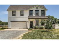 Charming two-story home featuring a white exterior, black trim, an attached garage, and a well-maintained lawn at 2206 Mills Harris Rd, Wingate, NC 28174