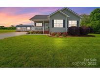 Charming single-Gathering home featuring a large front yard, cozy porch, and a detached storage shed at 2225 Corinth Church Rd, Monroe, NC 28112