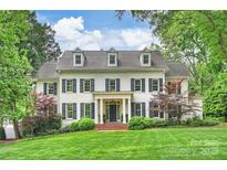 Stately white brick home featuring black shutters, dormer windows, and a manicured lawn at 3950 Abingdon Rd, Charlotte, NC 28211
