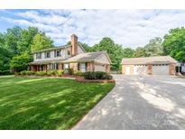 Charming two-story home featuring an attached garage, a detached three-car garage, and a well-manicured front lawn at 4145 Wrangler Sw Dr, Concord, NC 28027