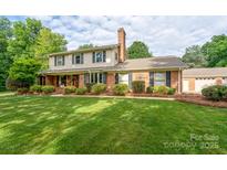 Charming two-story brick home featuring a large, well-manicured front yard with mature landscaping at 4145 Wrangler Sw Dr, Concord, NC 28027