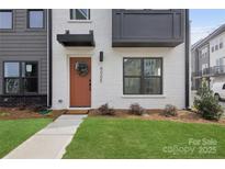 Stylish townhome exterior with brick, modern black accents, and a welcoming front door with green wreath at 6005 Countess Dr # 49, Charlotte, NC 28217