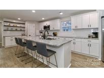 A bright, all-white kitchen with granite countertops, a large island, and stainless steel appliances at 703 S Main St, Landis, NC 28088