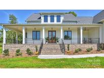 Inviting two-story white home with a brick foundation, grand staircase, and manicured front yard at 7768 Lynwood Ln, Sherrills Ford, NC 28673