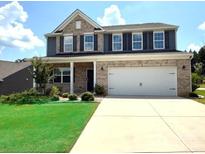 Two-story brick home featuring a two-car garage, manicured lawn and a welcoming front porch at 8901 Powder Works Dr, Huntersville, NC 28078