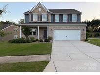 Traditional two-story home with a brick and blue facade, well-maintained lawn, and a two-car garage at 8901 Powder Works Dr, Huntersville, NC 28078