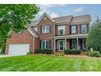 Charming brick home featuring a well-manicured lawn, a two-car garage, and classic black shutters at 8902 Whittingham Dr, Waxhaw, NC 28173