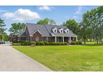 Stunning brick home boasts a sprawling lawn, mature trees, and a welcoming covered front porch at 172 Fairway Cir, Rock Hill, SC 29730