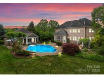 A luxurious backyard showcasing a large in-ground pool, well-manicured lawn, and beautiful landscaping with a house in the background at 2304 Thunder Gulch Ct, Waxhaw, NC 28173