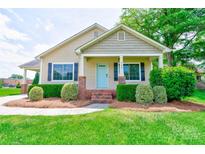 Charming single-Gathering home featuring a covered porch, a well-manicured lawn, and beautiful landscaping at 704 E Catawba St, Belmont, NC 28012