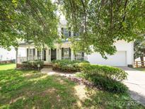 Charming two-story home with white siding, black shutters, covered front porch, and lush landscaping at 113 Rocky Trail Ct, Fort Mill, SC 29715