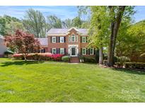 Charming two-story brick home featuring a lush, landscaped front yard with colorful flower beds at 14812 Stonegreen Ln, Huntersville, NC 28078