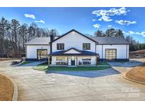 Stunning modern farmhouse with black trim, glass doors, covered porch, and manicured lawn on a sunny day at 1525 Shinnville Rd, Cleveland, NC 27013