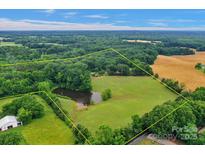 Expansive property featuring a private pond, surrounded by lush greenery and bordered by mature trees at 1607 Old Lawyers Rd, Marshville, NC 28103