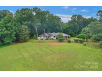 Sprawling ranch home on a large lot surrounded by mature trees and a wooden fence for added charm at 1607 Old Lawyers Rd, Marshville, NC 28103