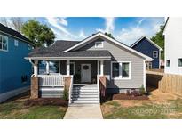 Inviting two-story gray home featuring fresh landscaping and a charming front porch with white stairs and railings at 2124 Roslyn Ave, Charlotte, NC 28208