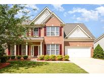 Charming two-story brick home featuring a well-manicured lawn, red shutters and a two-car garage at 3005 Sandbox Cir, Indian Trail, NC 28079