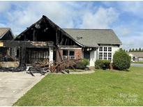 Fire-damaged one-story home with partial roof loss, driveway, and green lawn at 3205 Creek Trail Rd, Indian Trail, NC 28079