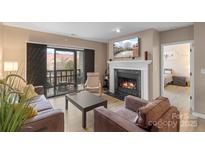 Cozy living room featuring a fireplace and sliding glass doors to a balcony with seating at 9029 J M Keynes Dr # 63, Charlotte, NC 28262