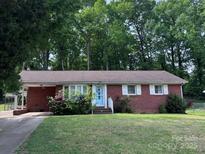 Charming brick home features a well-manicured lawn and inviting blue front door at 907 E 9Th Ave, Gastonia, NC 28054