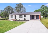 Charming single-story home with white brick, dark roof, front lawn, and covered parking area at 11 Cobblestone Nw Ln, Concord, NC 28027
