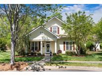 Charming two-story home with a well-manicured lawn, walkway, mature trees, and cozy front porch at 13216 Old Compton Ct, Pineville, NC 28134
