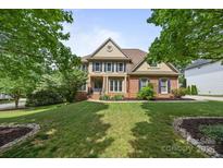 Charming brick home with manicured lawn and mature trees offers classic suburban living at 18305 Dembridge Dr, Davidson, NC 28036