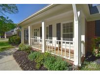 Inviting front porch with white columns, black shutters, and attractive landscaping at 317 Port Royal Dr, Matthews, NC 28105