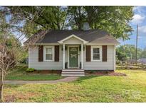 Charming cottage-style home with white siding, brown shutters, and a landscaped front yard at 506 Englewood Ne St, Concord, NC 28025