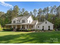 Charming two-story white farmhouse with a spacious front yard and inviting porch at 7351 Bay Cove Ct, Denver, NC 28037