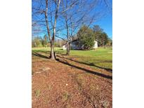 Exterior view of a small home with light colored siding surrounded by a large grassy yard at 908 E 1St St, Newton, NC 28658