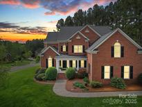 Charming two-story brick home featuring manicured landscaping and inviting front porch at sunset at 914 Olive Mill Ln, Matthews, NC 28104