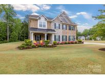 Charming two-story home with brick and stone exterior, landscaped yard and covered front porch with chairs at 4008 Pinot Way, Fort Mill, SC 29707