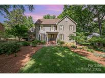 Traditional home boasts manicured lawn, mature trees, neutral paint, shutters, and covered entryway at 5206 Morrowick Rd, Charlotte, NC 28226