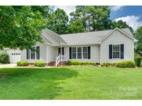 Charming single-story home featuring a well-manicured lawn, lush landscaping, and a classic white exterior at 605 Summey Farm Dr, Dallas, NC 28034