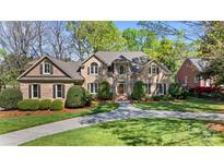 Elegant brick home featuring manicured landscaping, a circular driveway, and mature trees under a bright blue sky at 6202 Providence Country Club Dr, Charlotte, NC 28277
