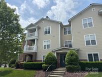 Charming condo building with two levels of porches, manicured landscaping, and inviting entrance at 9027 Mcdowell Creek Ln, Cornelius, NC 28031