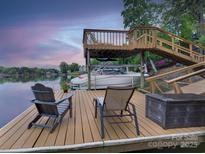 A waterfront dock area features a boat lift, seating, and picturesque lake views at sunset at 1114 Palmyra Dr, Tega Cay, SC 29708