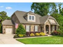 Charming home showcasing manicured lawn, stone accents, an American flag, and inviting curb appeal at 11424 Brangus Ln, Mint Hill, NC 28227