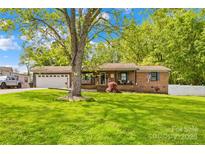 Charming brick home with a manicured lawn, mature shade tree, and an attached two-car garage at 1279 Rocky Creek Rd, Shelby, NC 28152