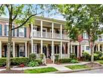 Charming brick townhouse with double porches, lush landscaping, and a welcoming American flag at 172 Harper Lee St, Davidson, NC 28036